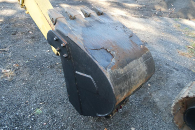 Excavator bucket attachment on Komatsu PC128US-8 showing worn bucket edge and wear plate.