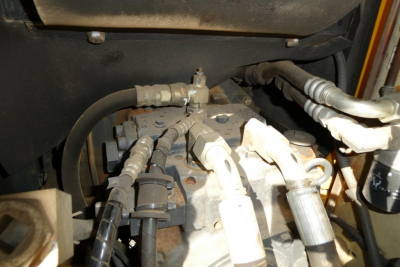 Komatsu PC128US-8 hydraulic manifolds and hoses with fittings in engine compartment view.