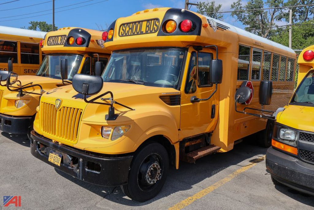 2013 IC Corporation AE Series school bus side view showing yellow body, front grille, and stop sign mirrors.
