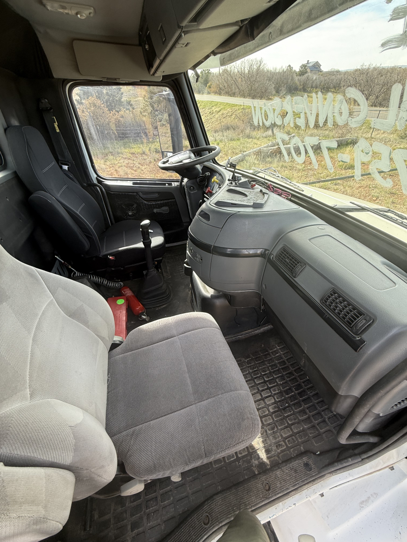 Volvo VNL64T300 truck cab interior showing steering wheel, driver seat, dashboard, and front passenger seat.
