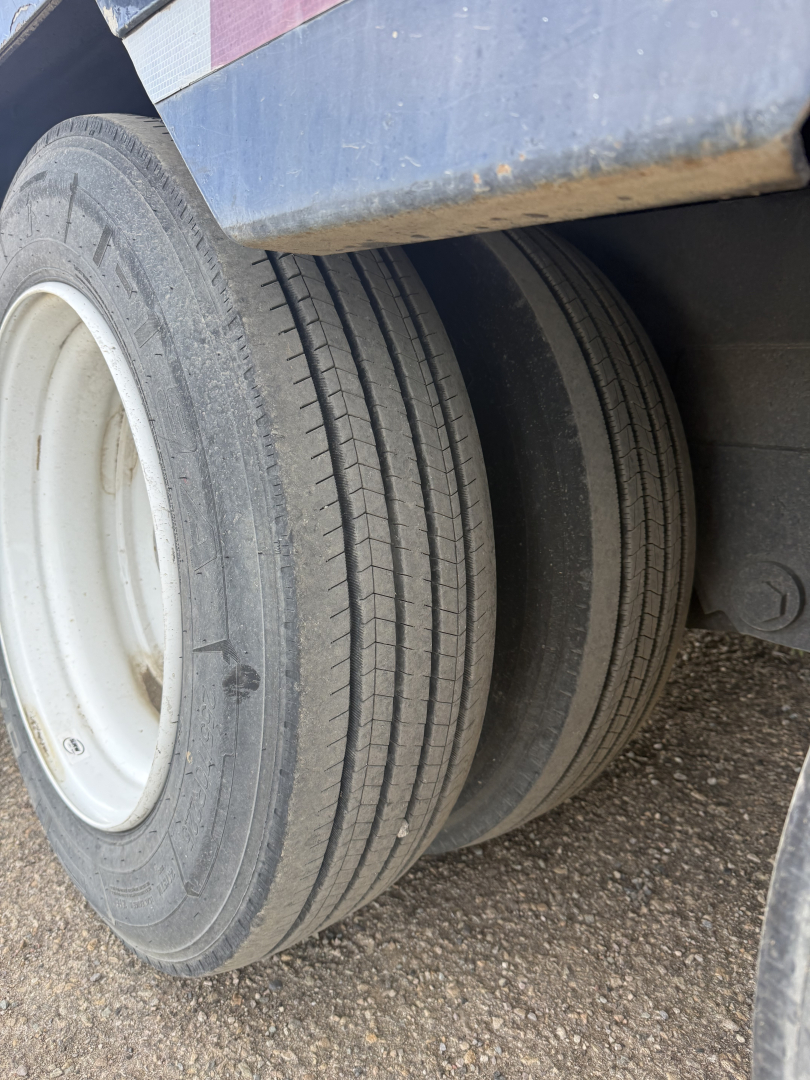 Dual rear wheels of a Volvo truck with tires showing tread and a blue body panel above; no legible text other than faint tire markings.