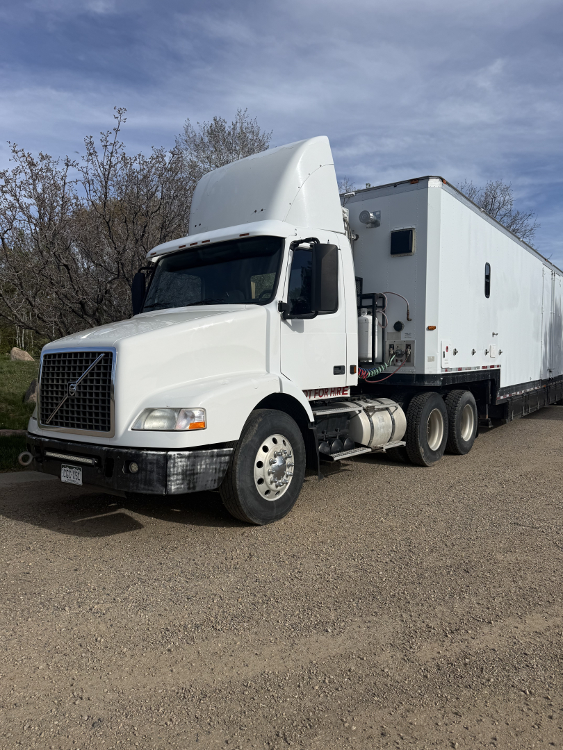 Volvo VNL64T300 tractor with a large sleeper cab and trailer in a dirt lot.