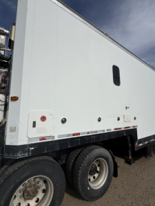 Truck side panel of a 2005 Volvo VNL64T300 box truck showing access panels, a small window, and dual rear wheels.