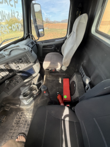 Volvo truck cabin interior showing driver seat and dashboard with controls and gear shifter.
