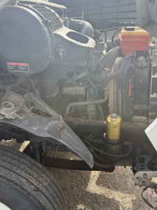 Volvo VNL64T300 truck engine bay with visible coolant reservoir, yellow oil filter, and various hoses and components.