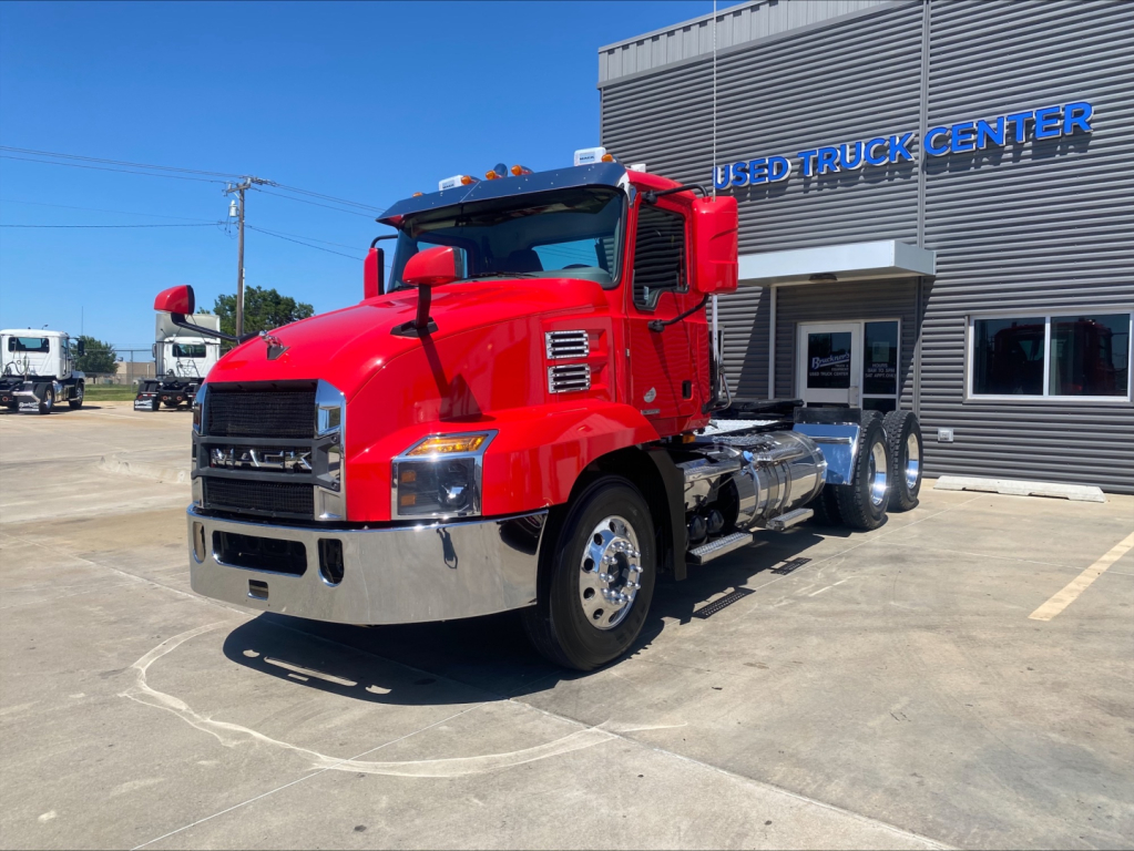Mack Anthem truck in red exterior with chrome bumper and dual rear axles at a used truck lot.