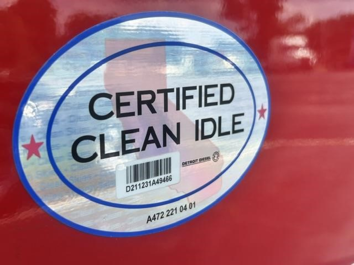 Certified Clean Idle sticker on red truck door with barcode and small text.