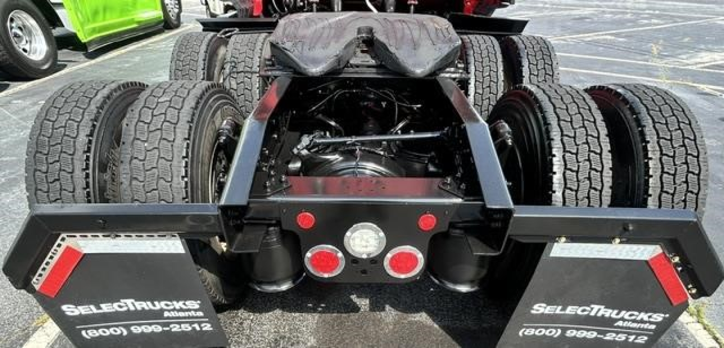 Rear view of a Freightliner Cascadia 126 tractor with fifth wheel plate and dual rear axles, multiple tires, and mud flaps showing SELECTtrucks branding.