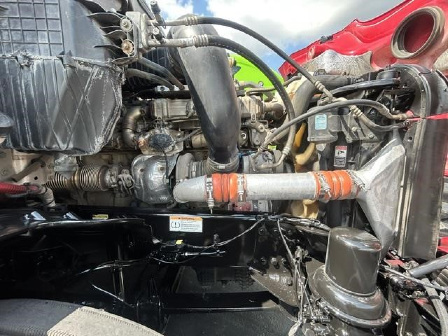 Freightliner Cascadia engine bay showing radiator, intercooler piping, hoses, and engine components in view.