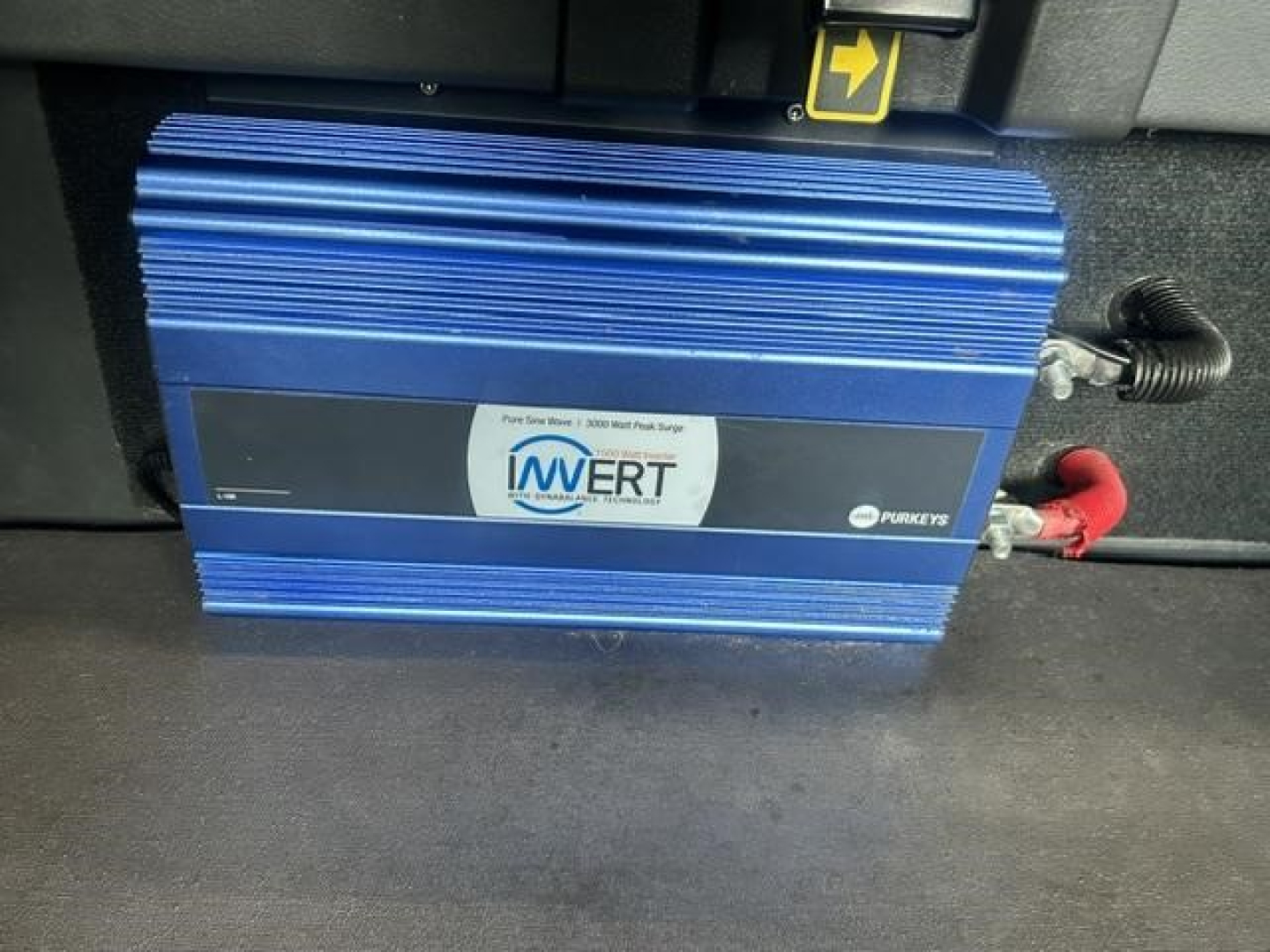 Blue Invert Pure Sine Wave inverter mounted in Freightliner Cascadia sleeper truck with red and black cables connected.