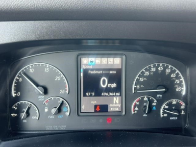 Dashboard cluster of Freightliner Cascadia showing digital display with 0 mph and various gauges. Center display shows speed, odometer 496,364 mi, 97°F outside temp. Left gauges include tachometer and fuel, right gauges include air pressur