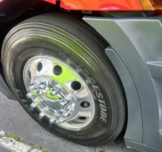 Front wheel and fender of Freightliner Cascadia 126 showing Bridgestone tire and chrome hubcap.