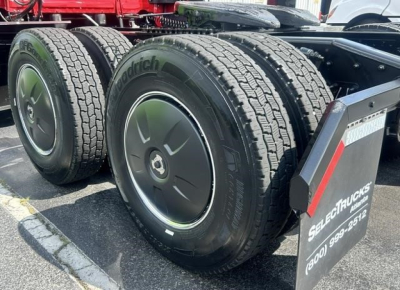 Freightliner Cascadia 126 rear dual axle tires shown with BFGoodrich or Michelin tires and wheel covers; wheel tags and a sign display nearby.