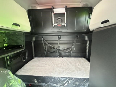 Freightliner Cascadia sleeper cab interior shows bed area with storage compartments and ladder mounting points.
