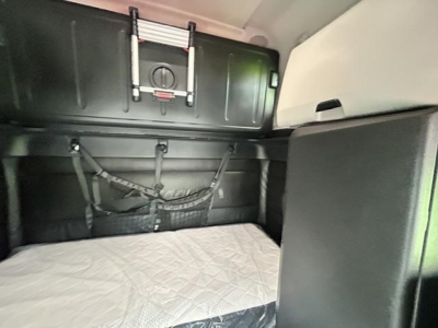 Freightliner Cascadia cab interior storage area with sleeper bed and overhead compartments.