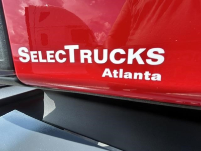 Truck side panel with 'SELECTRUCKS Atlanta' branding on red paint, partial view of a Freightliner Cascadia 126 listing context text visible.