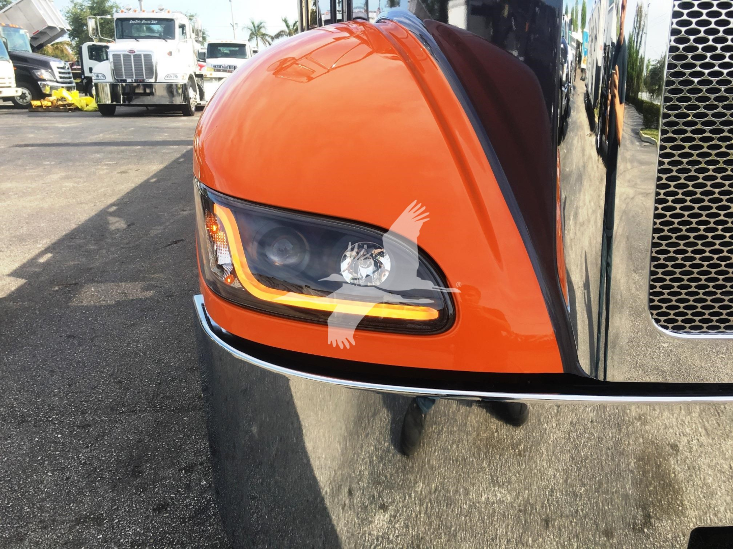 Peterbilt 337 front corner showing orange fender and headlight with chrome grille crossbar.