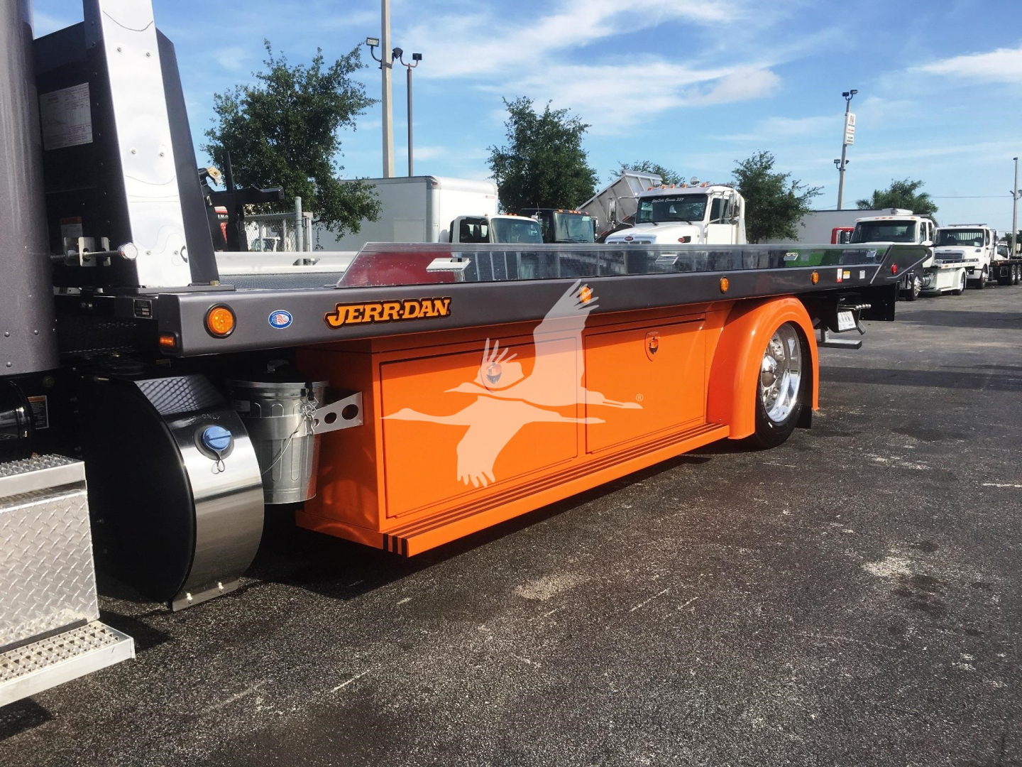 Peterbilt 337 rollback truck body showing orange painted lower panel with Jerr-Dan branding and silhouette graphic, flatbed with orange accents.