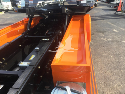 Peterbilt 337 rollback truck body with bright orange paint and black chassis components visible in the bed area