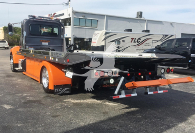 Peterbilt 337 rollback crane truck in orange and black with flatbed and lift equipment visible, rear view showing taillights and equipment rack.