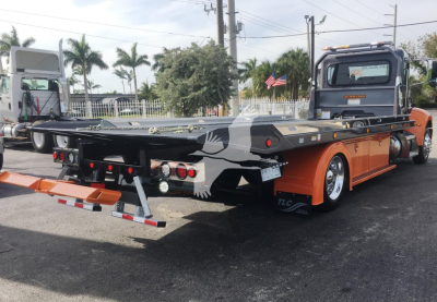 Peterbilt 337 rollback truck showing flatbed and rear lights, orange and black color scheme, rear view with winch and towing equipment.