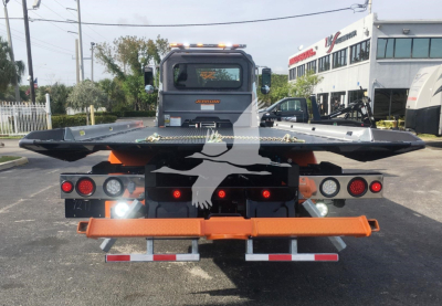 Peterbilt 337 rollback truck rear view showing hydraulic bed and taillights with orange safety beacon and bumper.