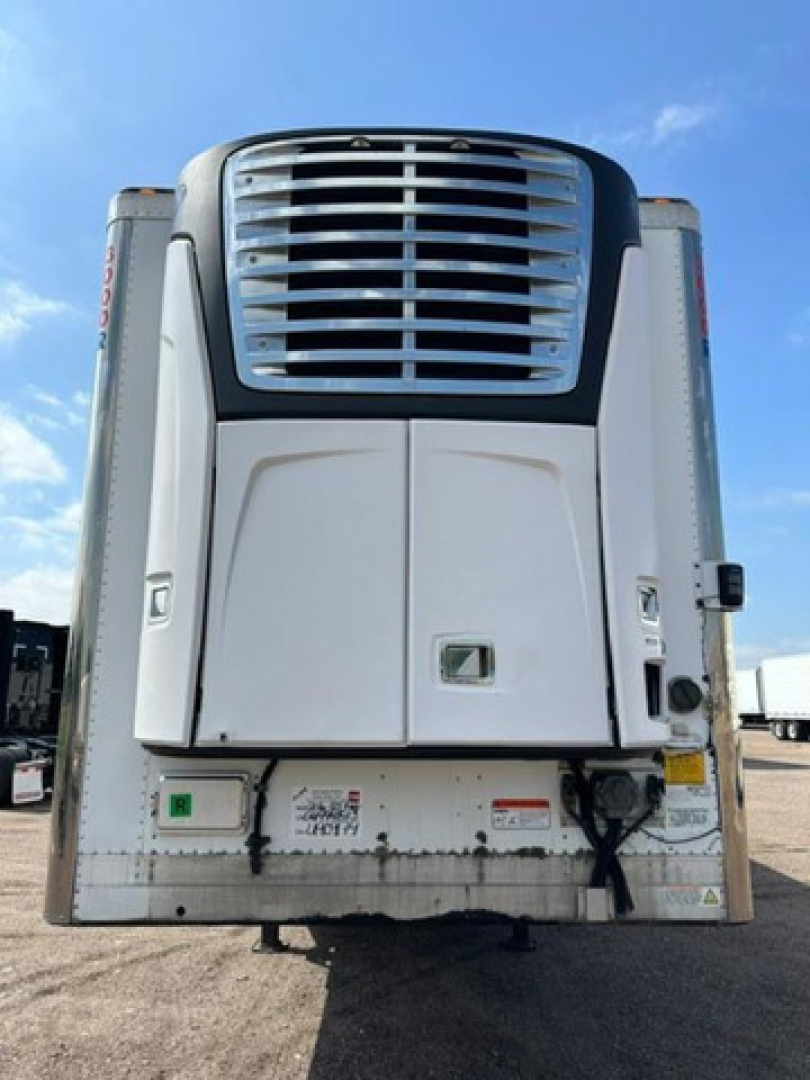 Trailer rear view showing refrigeration unit and bumper with various stickers and connectors.