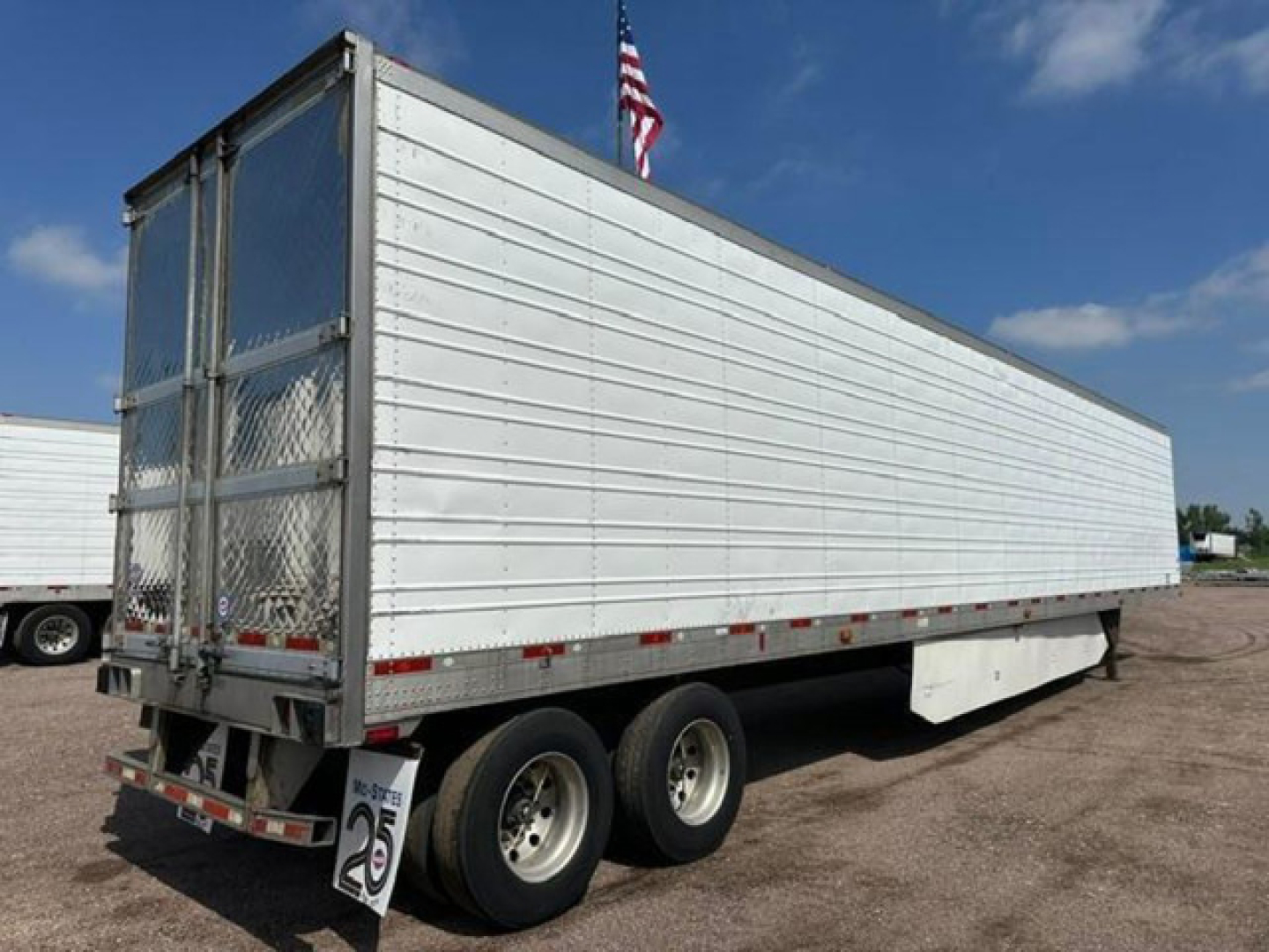 Trailer side view showing a 2016 utility reefer, white refrigerated trailer with dual rear doors and stabilizing legs, stock number U90979.