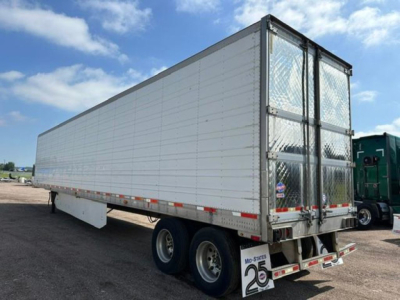 Trailer side and rear showing tandem axles, white reefer trailer, aluminum doors with lattice pattern on rear, metal framing, reflective strips.