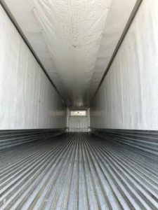 Trailer interior showing corrugated metal floor and white sidewalls, long narrow cargo area viewed from rear opening