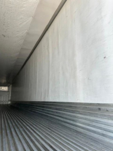 Trailer interior showing ribbed floor and metal side walls in a refrigerated trailer.