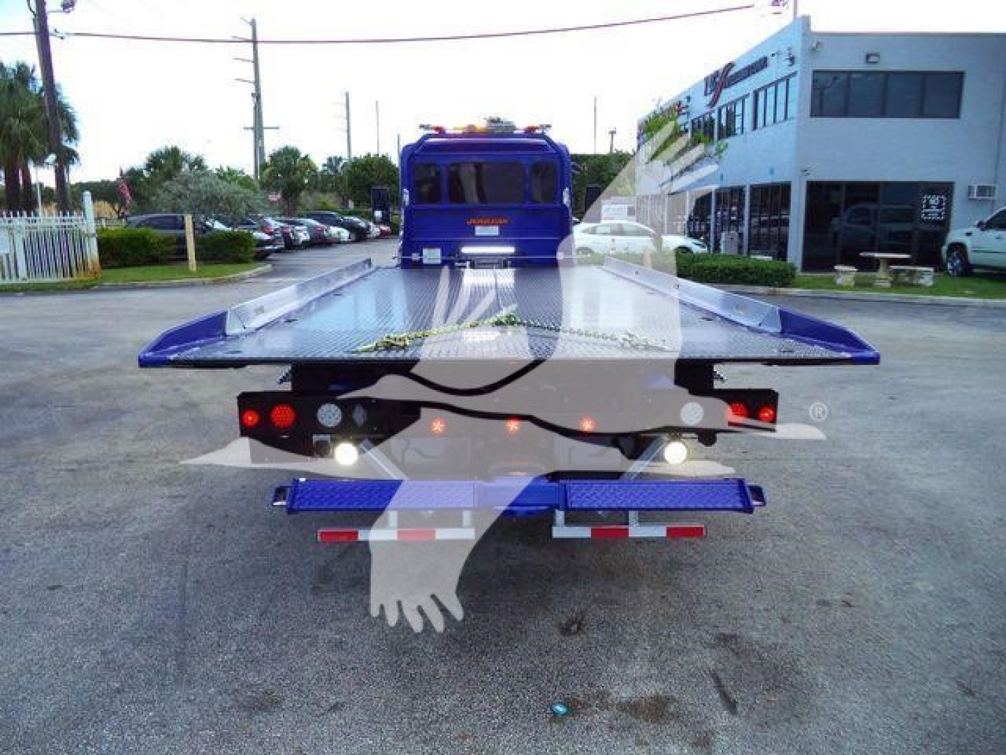 Back view of a blue 2025 Peterbilt 536 rollback truck with a raised flatbed and dual rear taillights.