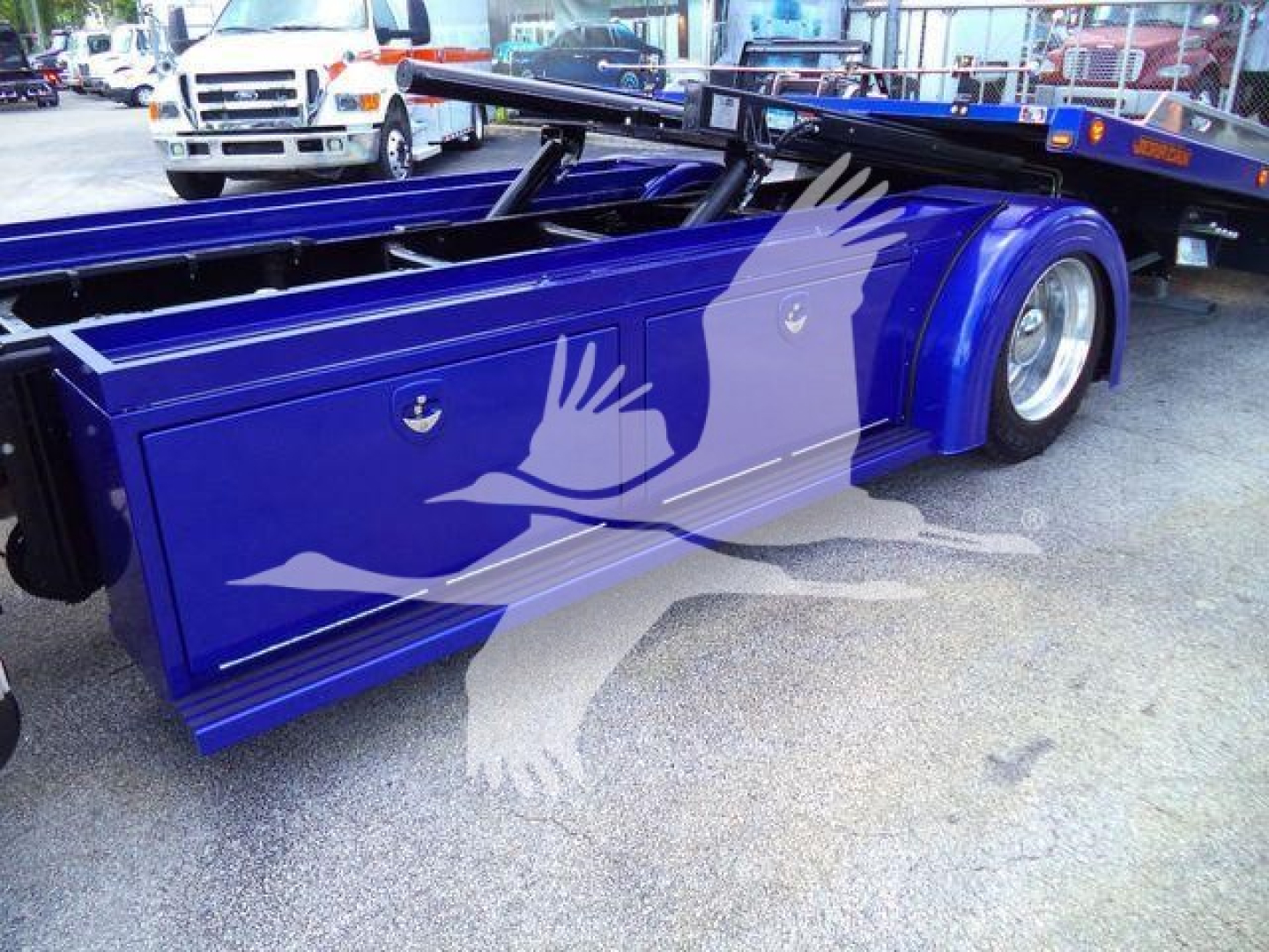 Peterbilt 536 rollback truck side view showing purple-blue body panels with storage compartments and wheel wells.