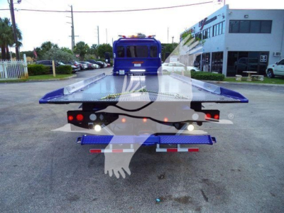 Back view of a blue 2025 Peterbilt 536 rollback truck with a raised flatbed and dual rear taillights.