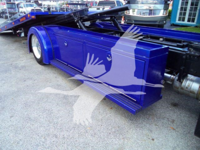 Blue Peterbilt 536 rollback bed platform shown in side view with storage compartments and hydraulic lines.