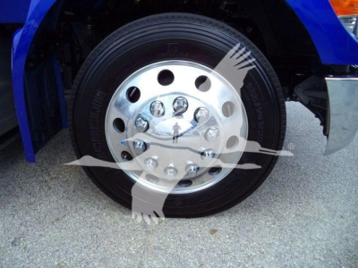 Front wheel of a Peterbilt truck showing a large polished steel wheel with hub, lug nuts, and black tire.