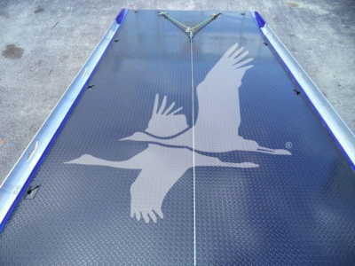 Trailer deck with a large white bird graphic on blue diamond-plate surface and metal rails at the sides.