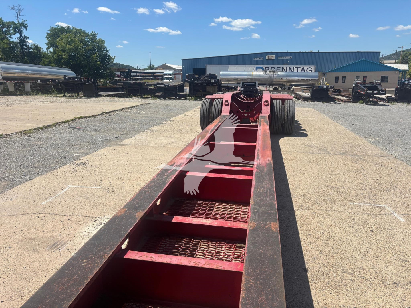 Beam trailer chassis showing red painted main frame with stepped chassis steps and dual rear axles in distance.