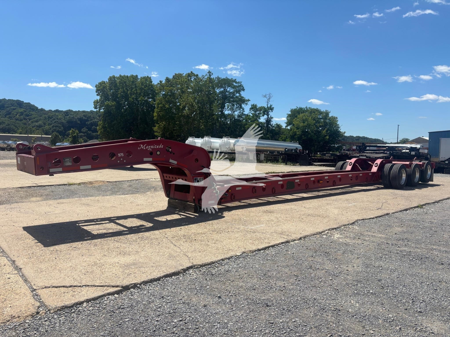 Lowboy trailer in red with Fontaine beam, extended sections, and dual rear axles showing undercarriage and hitch area.