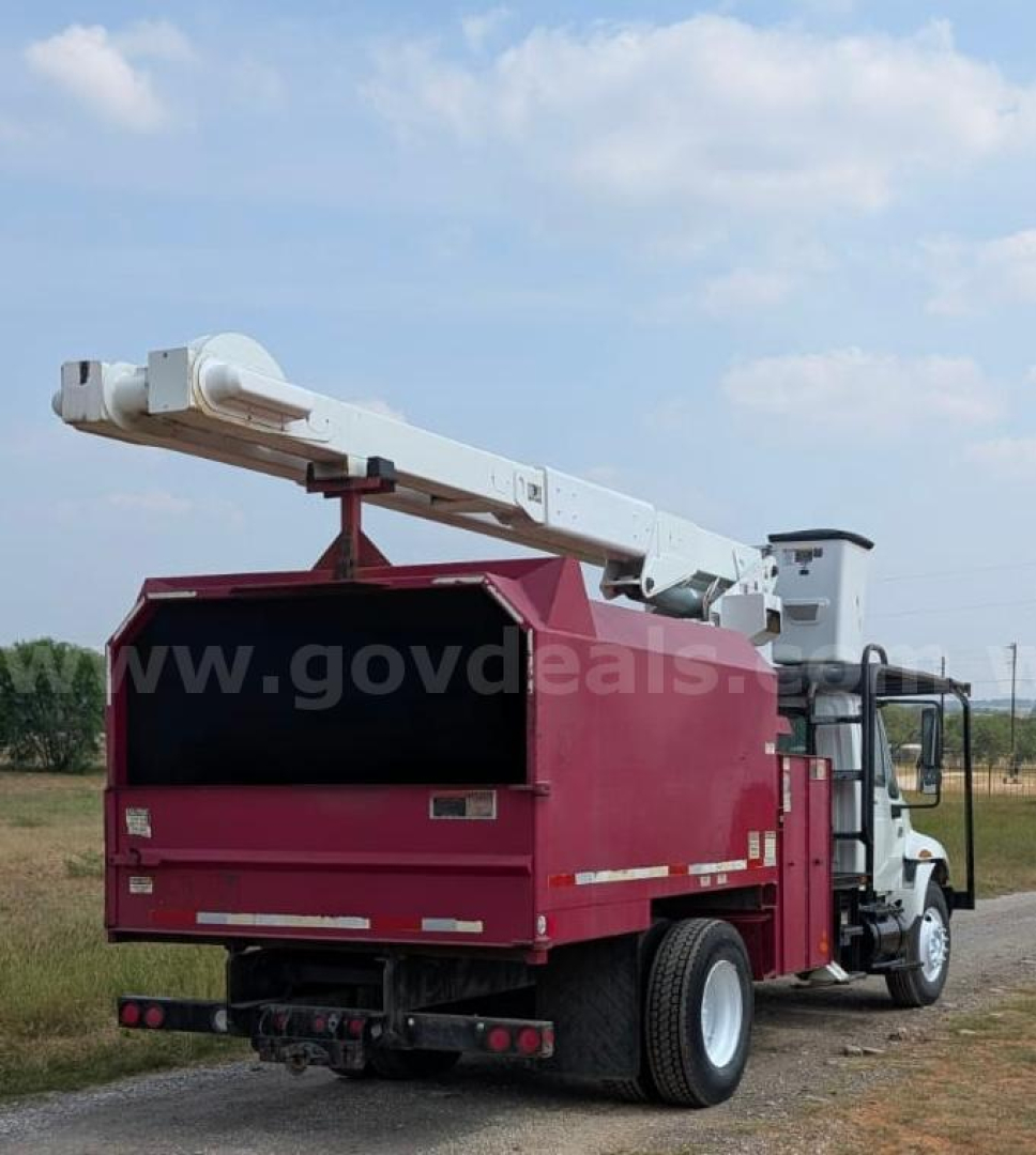 Truck bucket lift with hydraulic boom, bucket body in maroon, cab in white, rear view with extended boom.