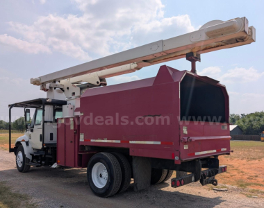 Truck-mounted platform bucket truck with a pinkish red bucket body and white crane arm, rear view showing stabilizers and rear bumper.