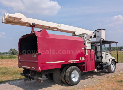 Bucket truck with a white cab and pink utility bed, long boom crane extended over top, side view showing dual rear wheels.