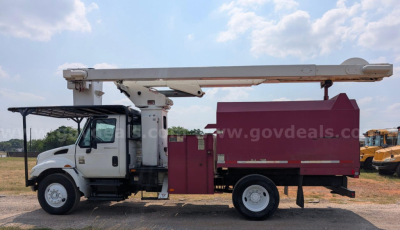 Truck bucket lift body with white cab and purple service bed, long boom raised on top; appears to be International DT466 diesel truck in service.