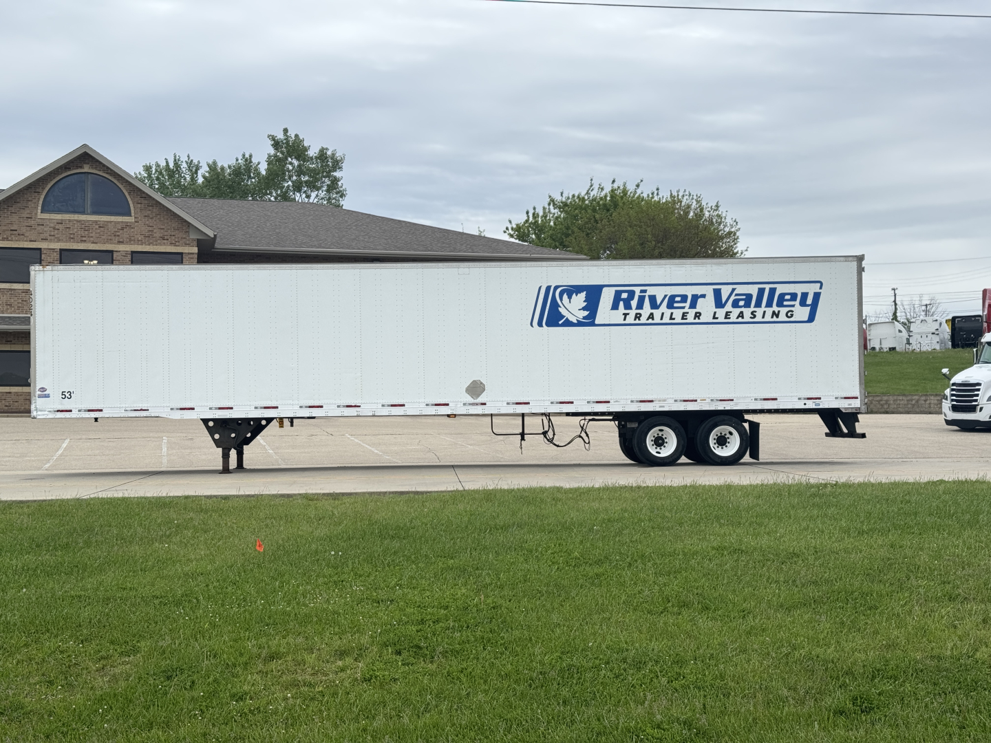 Utility trailer showing River Valley Trailer Leasing graphic on white trailer with dual axles and front landing gear.