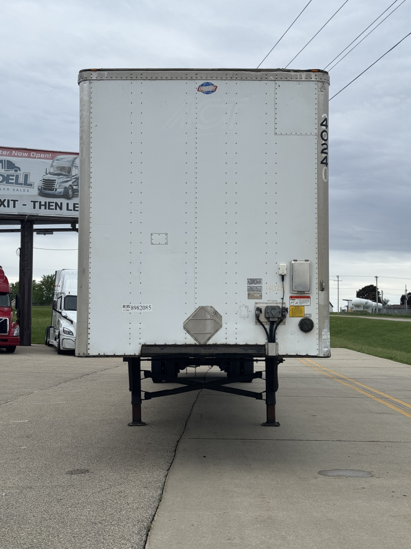 Rear view of a white Utility 4000DX trailer with tall jacks down, VIN/stock details faint, and '4000DX' marking on right edge.