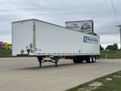Utility 4000Dx trailer in a parking lot showing raised riveted aluminum siding, dual rear axles, and a River Valley trailer logo on the side.