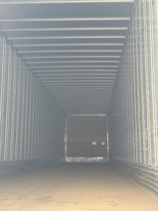 Trailer interior showing cargo area with metal walls and floor; rear door with cutout and small rectangular feature.