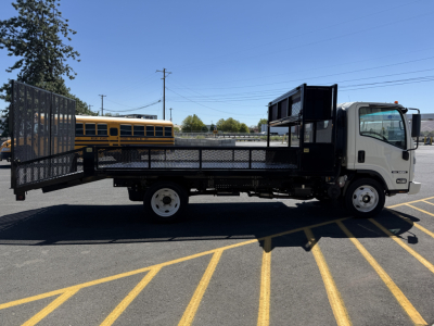 Isuzu flatbed truck with powder-coated black steel flatbed and ramp, side view showing cab, cargo area, and hitch.