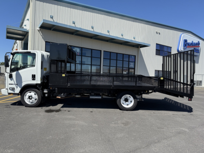 Isuzu NQR flatbed truck with a loading ramp and utility bed in a dealership lot, side view showing cab and cargo area.