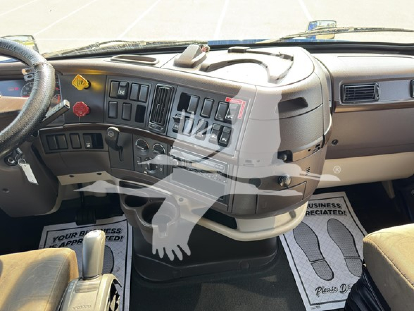 Volvo truck cab dashboard and steering wheel view of a 2017 Volvo VN turbodiesel sleeper with multiple control switches and grey interior.